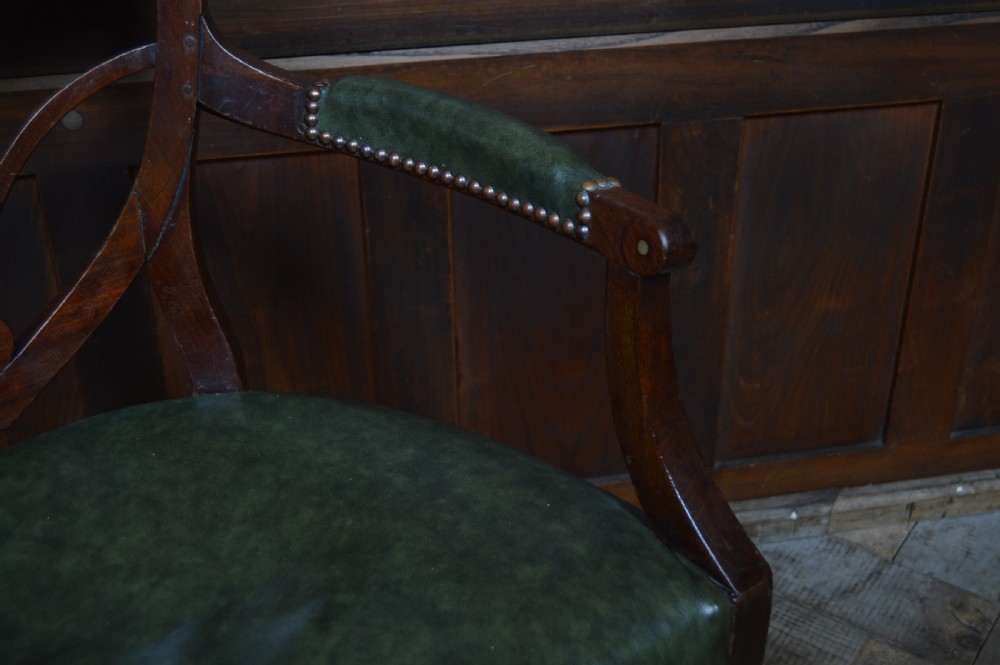 A Regency mahogany open armchair featuring a fan-shaped carved back splat with brass inlay, green leather seat with brass studs, and padded armrests. View VI
