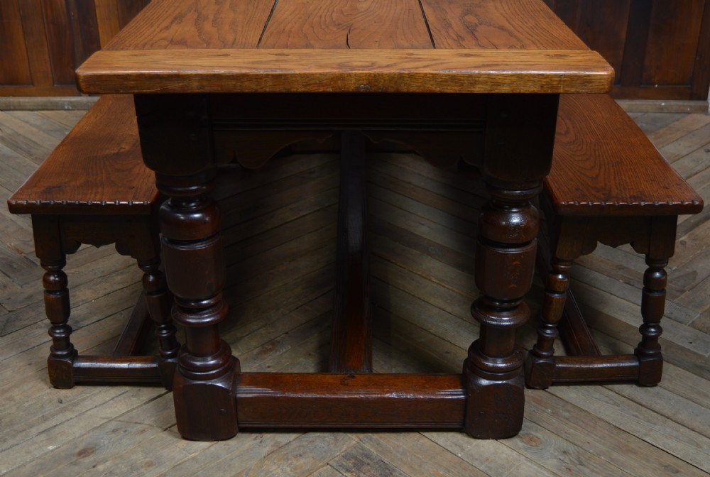 A 19th-century solid oak refectory dining table featuring a plank top and turned legs, flanked by two matching wooden benches. View III