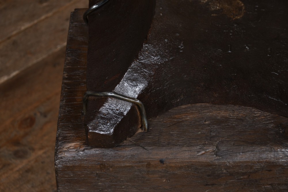 A heavy dark cast iron blacksmith anvil mounted on a weathered square timber block. View IX