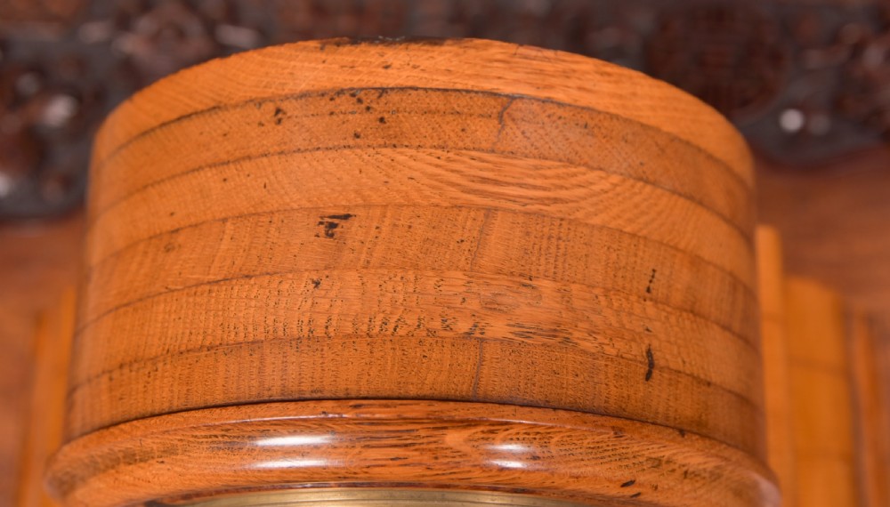 An antique oak mantel clock featuring a rounded arch case, brass dial with Roman numerals, marked Thwaites and Reed London, raised on brass bun feet. View V