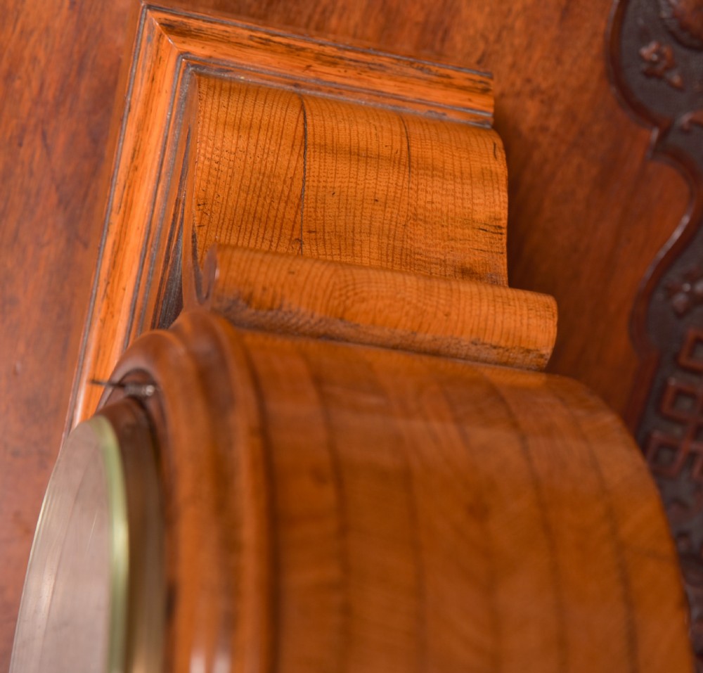 An antique oak mantel clock featuring a rounded arch case, brass dial with Roman numerals, marked Thwaites and Reed London, raised on brass bun feet. View VI