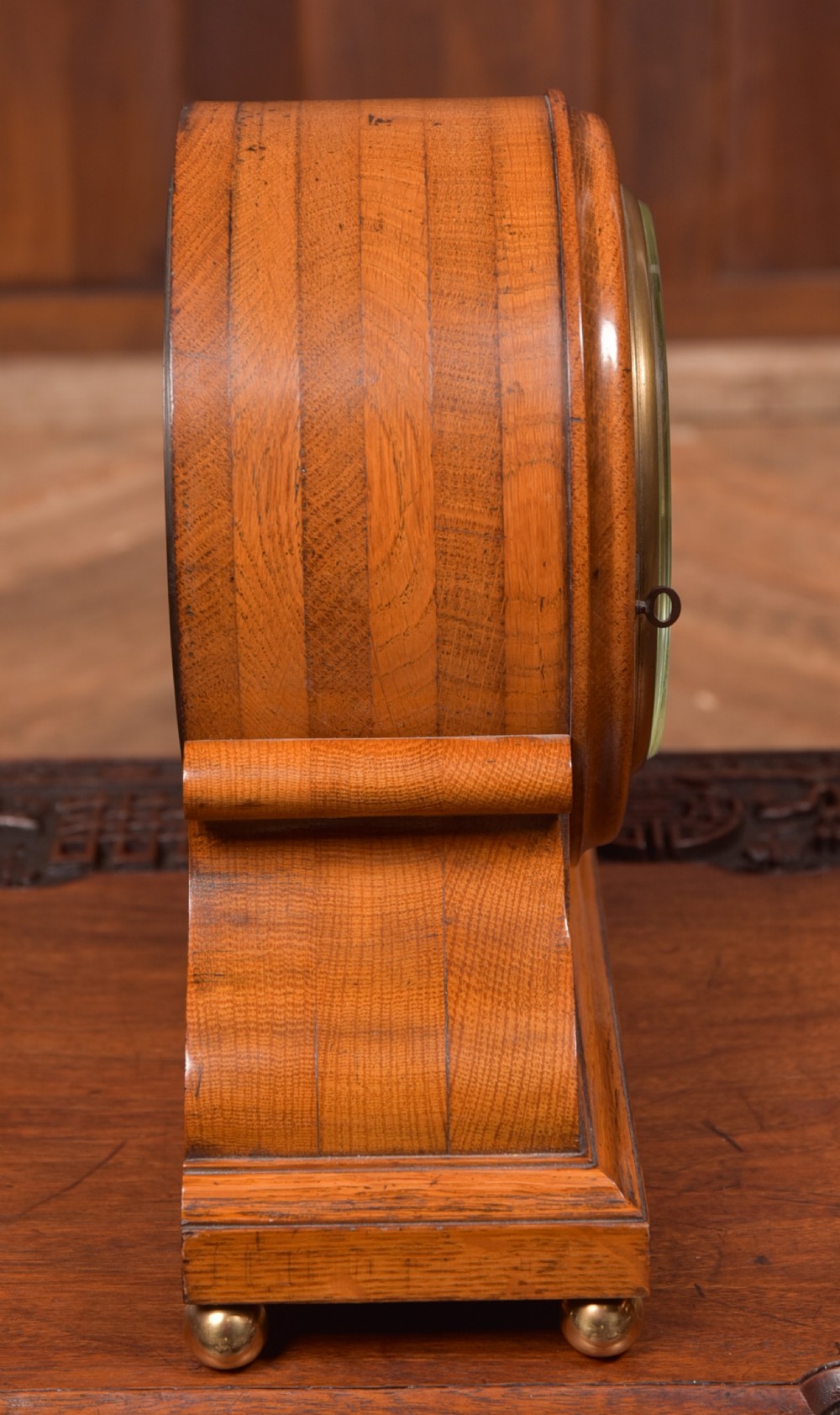 An antique oak mantel clock featuring a rounded arch case, brass dial with Roman numerals, marked Thwaites and Reed London, raised on brass bun feet. View IX