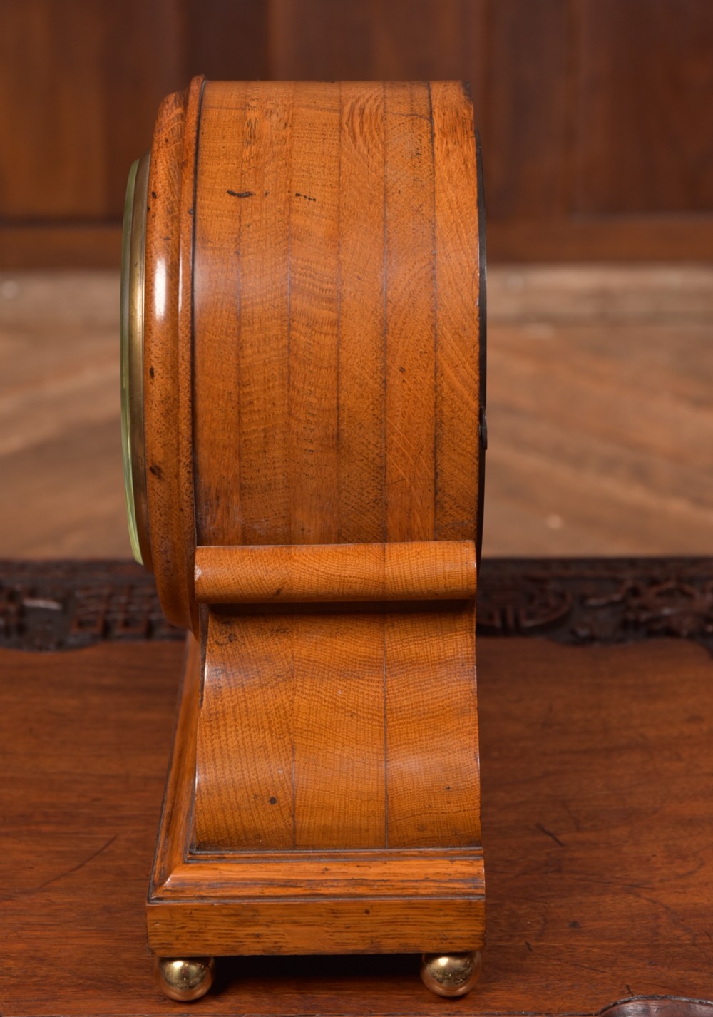 An antique oak mantel clock featuring a rounded arch case, brass dial with Roman numerals, marked Thwaites and Reed London, raised on brass bun feet. View XI