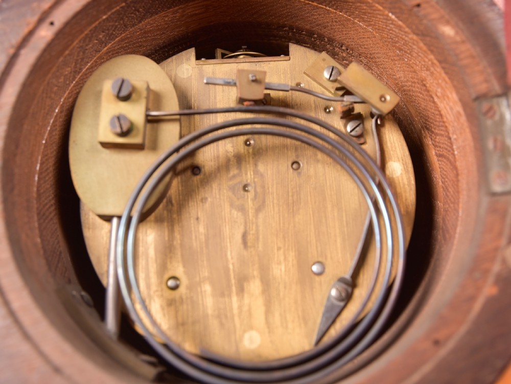 An antique oak mantel clock featuring a rounded arch case, brass dial with Roman numerals, marked Thwaites and Reed London, raised on brass bun feet. View XIII