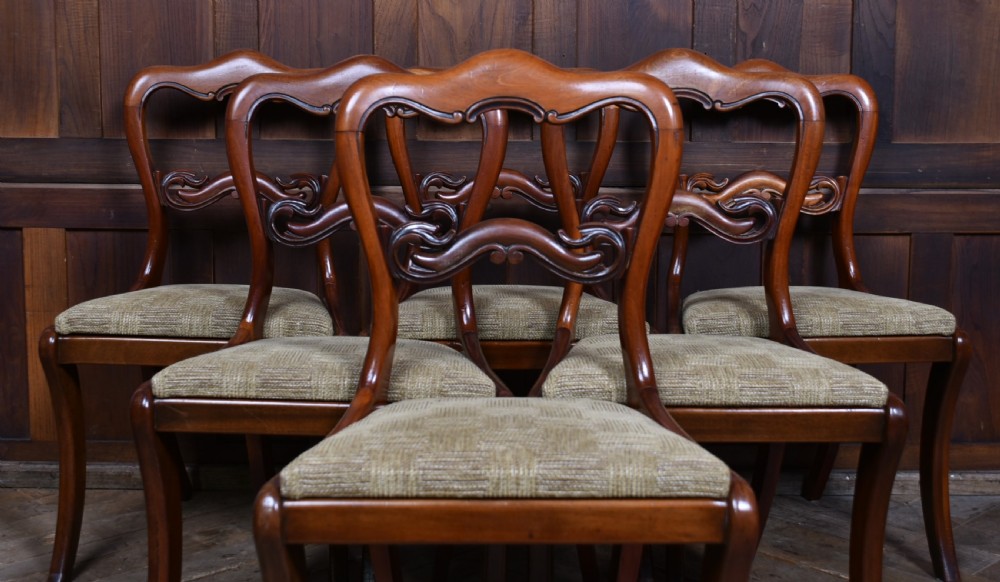A set of six Victorian walnut balloon back dining chairs featuring hand-carved openwork back splats, cabriole legs, and textured beige upholstery. View IV