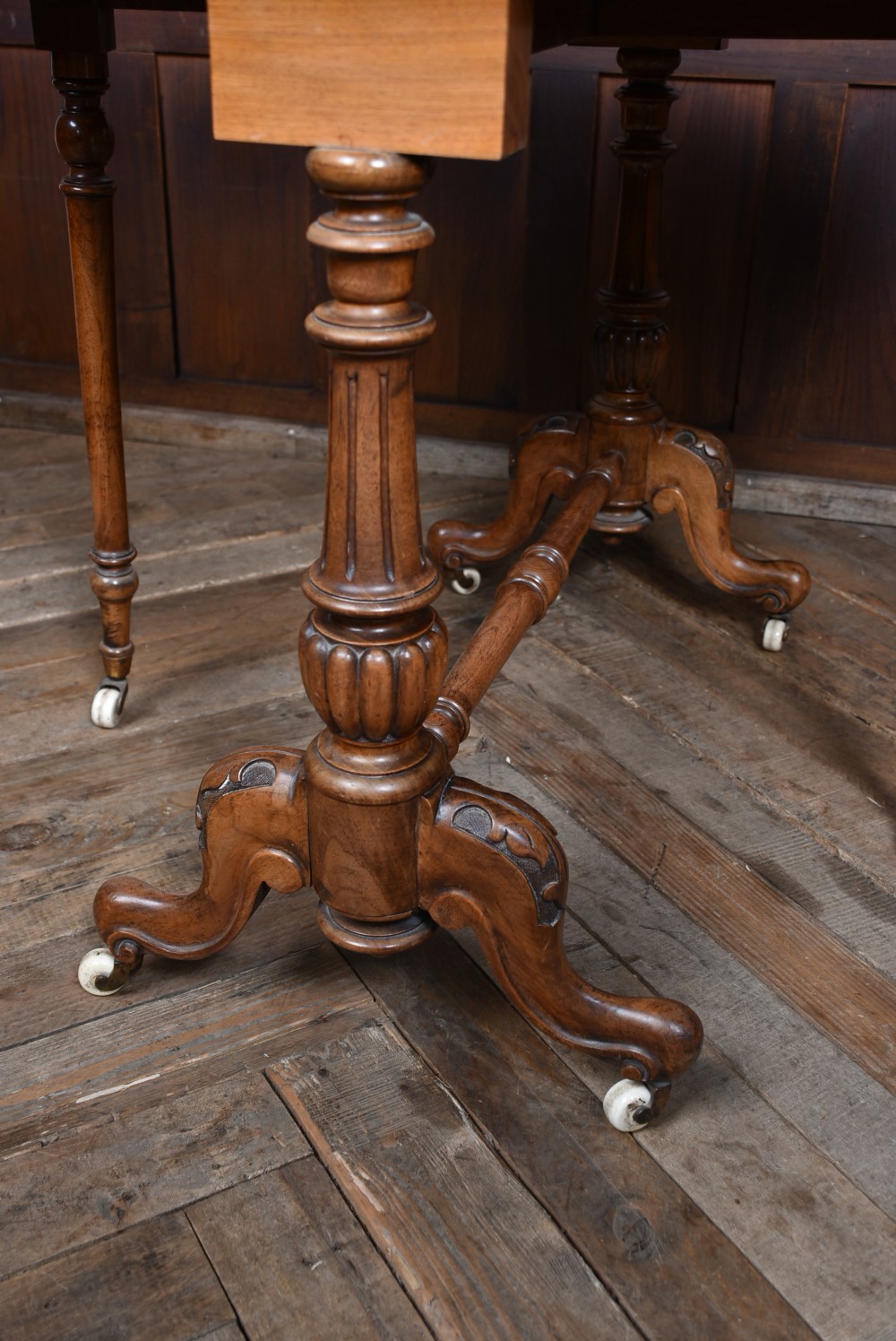 A Victorian burr walnut Sutherland table featuring hinged drop leaves, turned twin supports, carved cabriole feet, and white ceramic castors. View XIII