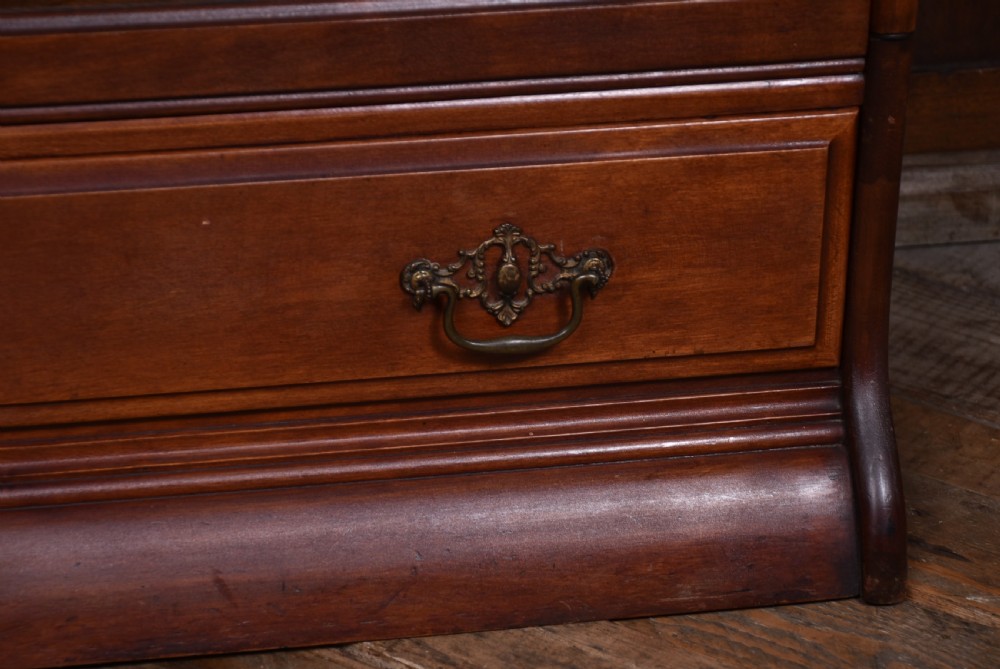 An Edwardian mahogany three-tier sectional bookcase featuring glazed lift-up doors and a bottom drawer with decorative brass handles. View V