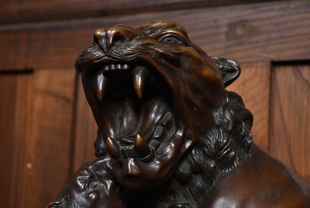 A dark patinated bronze sculpture depicting a snarling tigress protecting her two cubs on a textured ground base. View VII