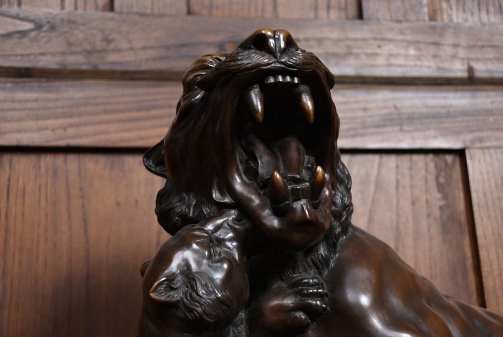 A dark patinated bronze sculpture depicting a snarling tigress protecting her two cubs on a textured ground base. View VIII