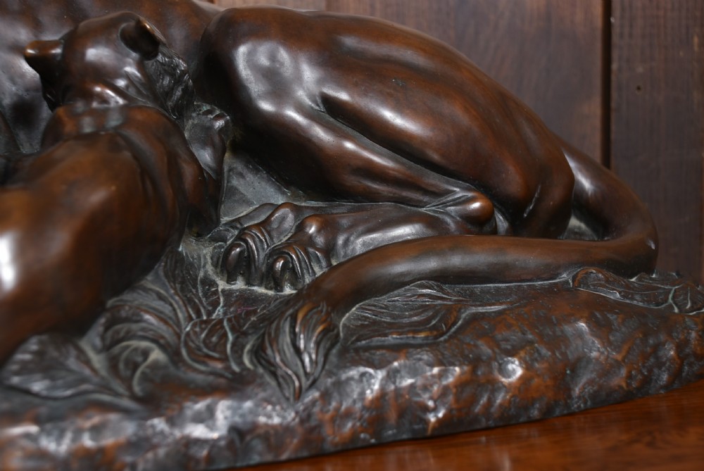 A dark patinated bronze sculpture depicting a snarling tigress protecting her two cubs on a textured ground base. View XI