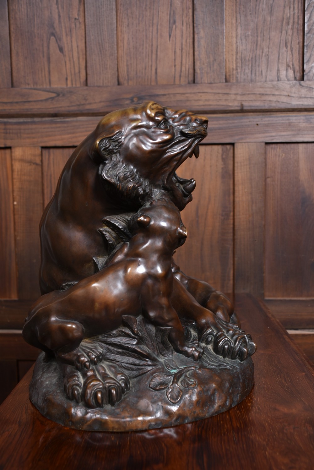 A dark patinated bronze sculpture depicting a snarling tigress protecting her two cubs on a textured ground base. View XIII