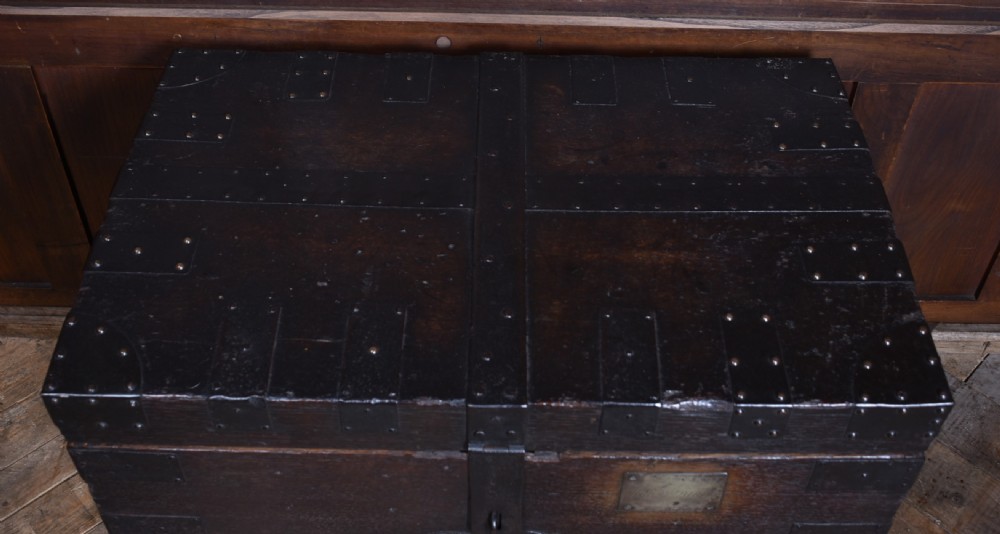 A dark oak Victorian silver chest featuring heavy black iron straps, corner brackets, studded detailing, and an engraved brass plaque on the front. View IX