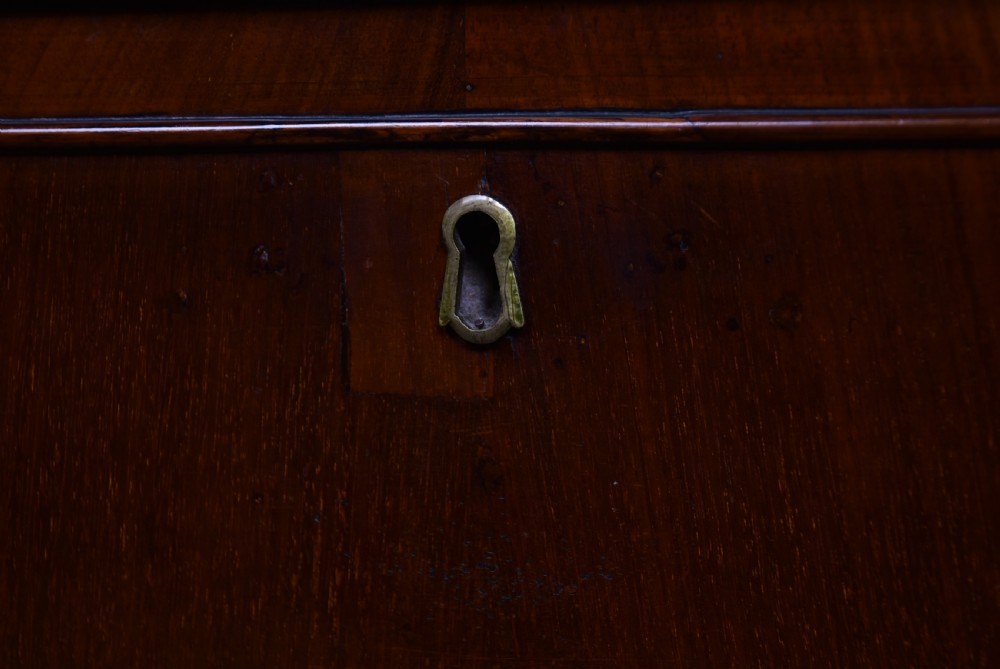 An antique walnut cylinder bureau featuring three full-width drawers with cast brass drop handles and keyhole escutcheons. View IX