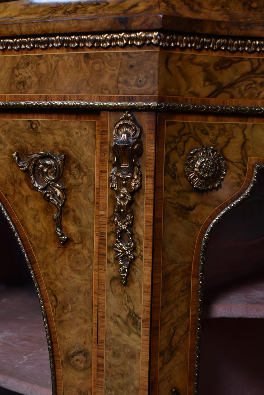 A Victorian burr walnut credenza featuring glazed doors, delicate marquetry inlay, and decorative gilt-metal mounts. View V
