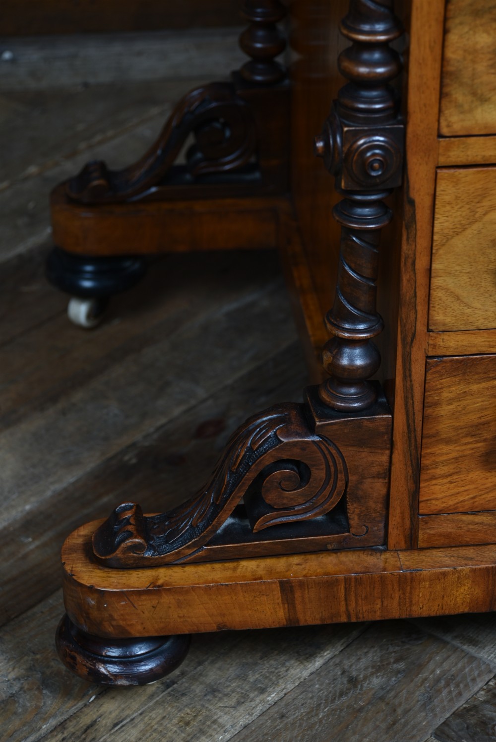 A Victorian burr walnut Davenport desk featuring a slanted brown leather writing top, carved front support columns, side drawers, and castors. View XIII