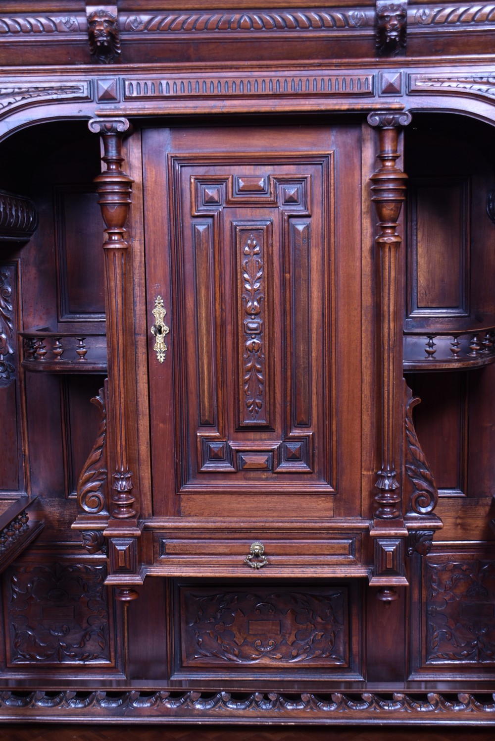 A pair of ornate dark walnut two-tier Continental cabinets featuring intricate carvings, turned columns, geometric panelled doors, and parquetry tops. View VI