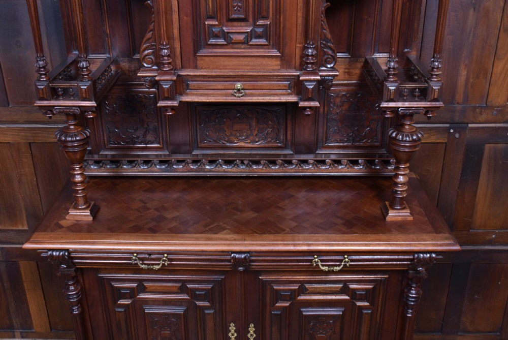 A pair of ornate dark walnut two-tier Continental cabinets featuring intricate carvings, turned columns, geometric panelled doors, and parquetry tops. View IX