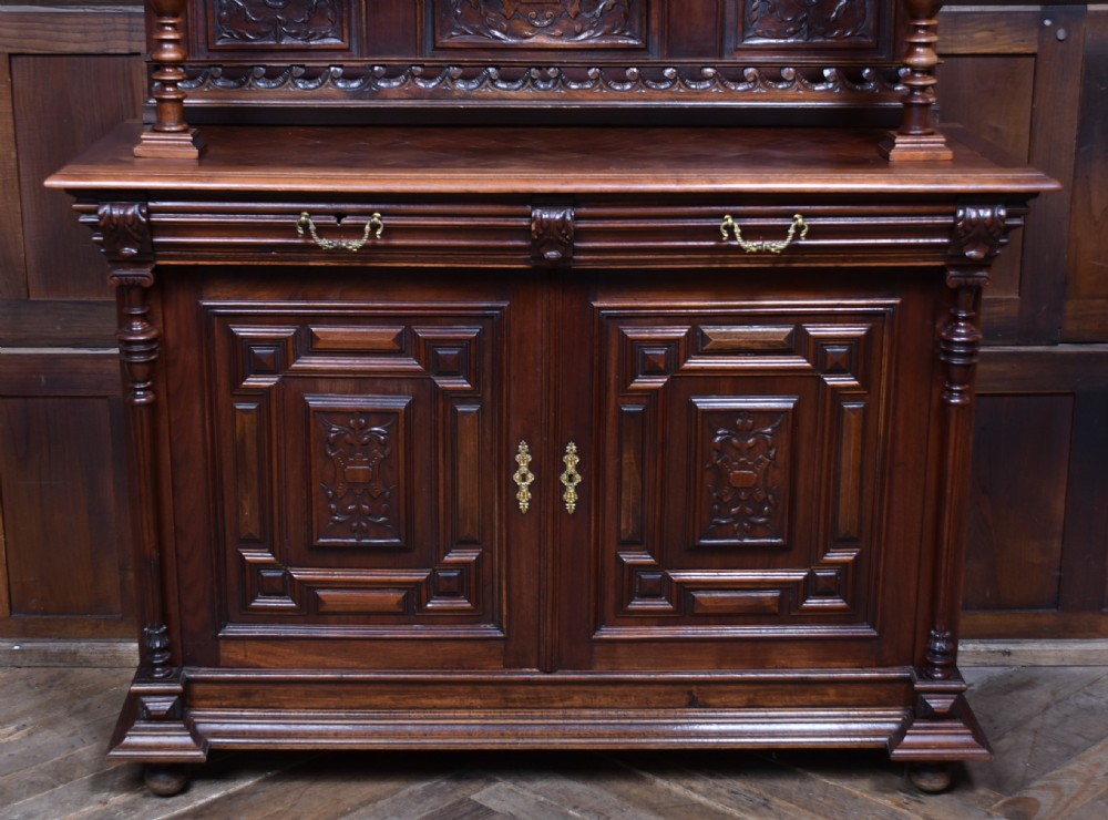 A pair of ornate dark walnut two-tier Continental cabinets featuring intricate carvings, turned columns, geometric panelled doors, and parquetry tops. View X