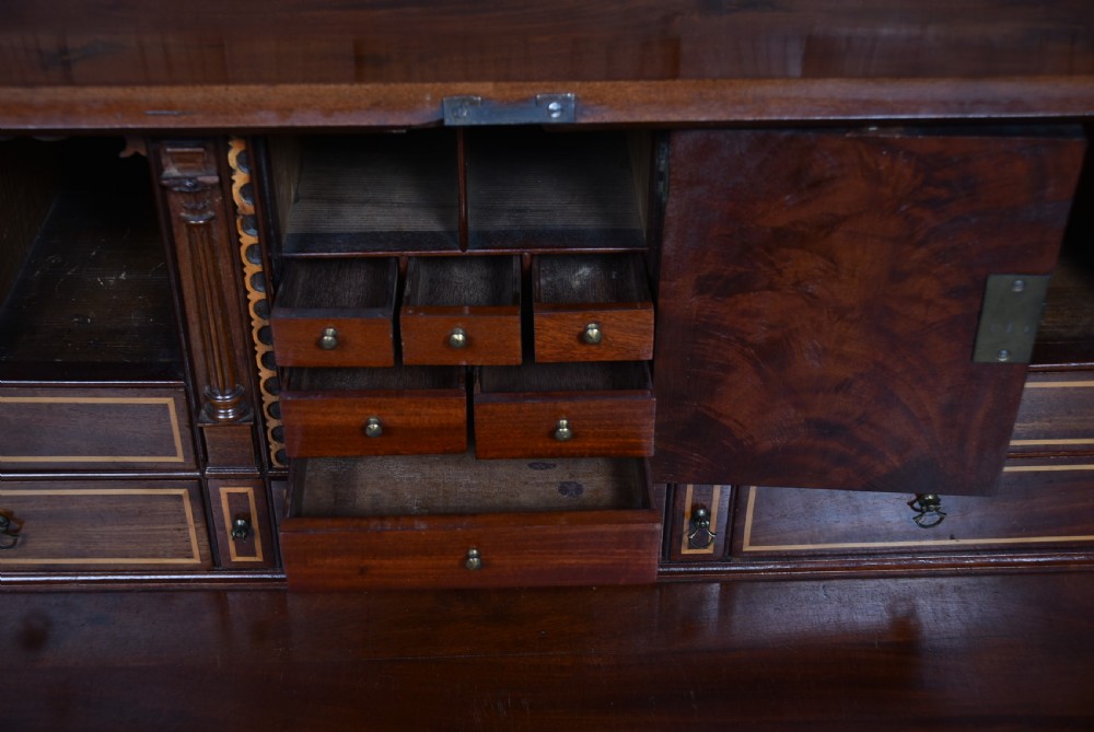 An antique Georgian mahogany slant-front writing bureau featuring four graduated drawers with brass handles and central oval marquetry inlay on the fall flap. View XII