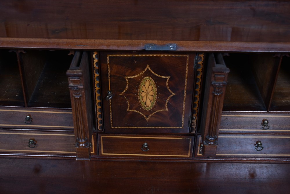 An antique Georgian mahogany slant-front writing bureau featuring four graduated drawers with brass handles and central oval marquetry inlay on the fall flap. View XIII