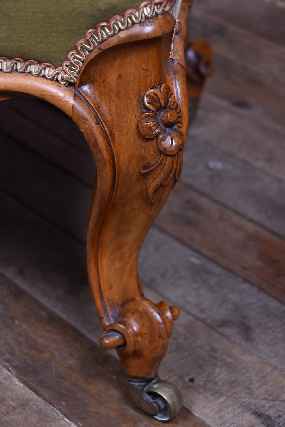 A low Victorian walnut centre stool with carved cabriole legs on brass castors, upholstered in a black floral needlepoint top with green velvet sides. View IX
