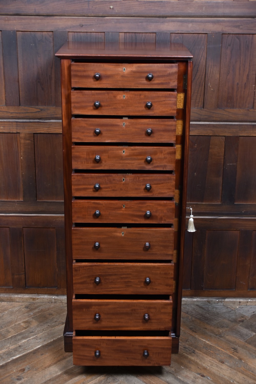 A tall Victorian mahogany Wellington chest with nine drawers, turned handles, and a side locking bar. View XIII