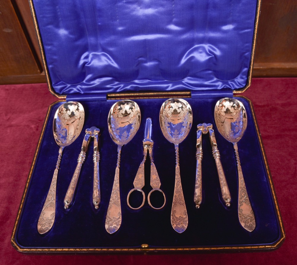 An antique cased silver-plate fruit and nut serving set with four engraved spoons, two nutcrackers, and grape shears set in a cobalt blue velvet lining. View V