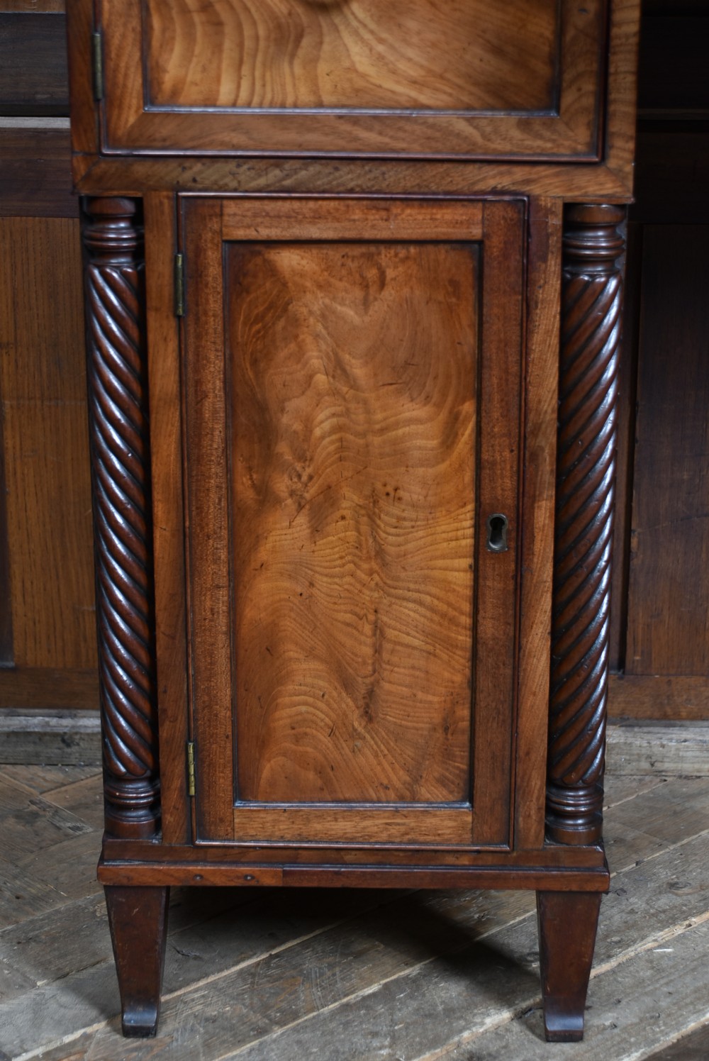 A Regency flame mahogany pedestal sideboard featuring side cupboard pedestals with spiral rope-twist columns, a central drawer section, brass ring handles, and a low rear gallery. View XI