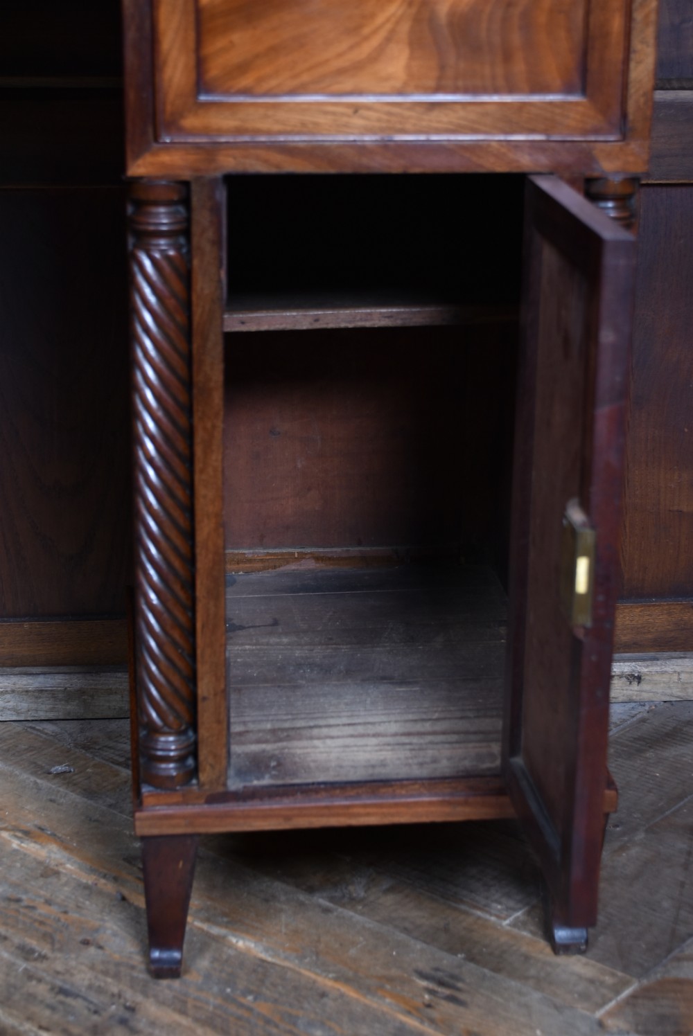 A Regency flame mahogany pedestal sideboard featuring side cupboard pedestals with spiral rope-twist columns, a central drawer section, brass ring handles, and a low rear gallery. View XII