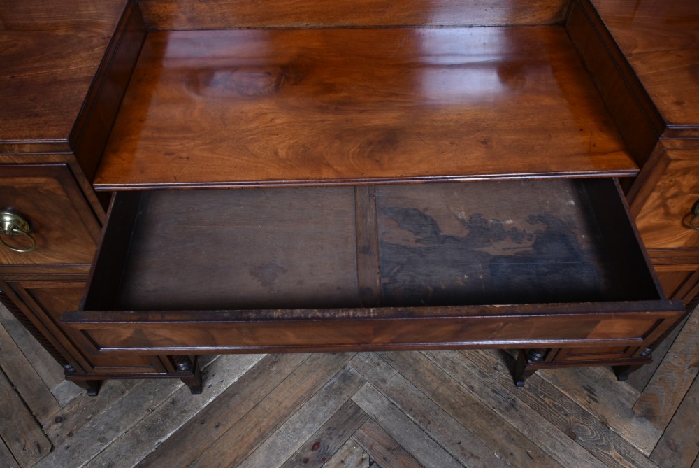 A Regency flame mahogany pedestal sideboard featuring side cupboard pedestals with spiral rope-twist columns, a central drawer section, brass ring handles, and a low rear gallery. View XIII