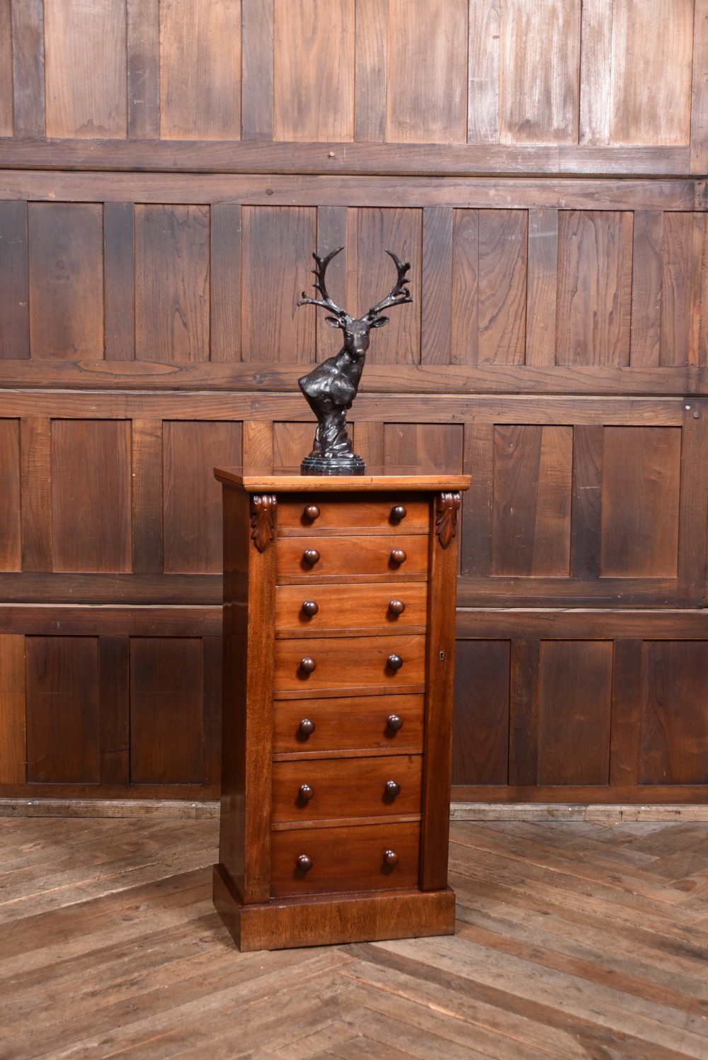 A tall Victorian mahogany Wellington chest featuring seven graduated drawers with turned knobs and a carved side locking pilaster. View II