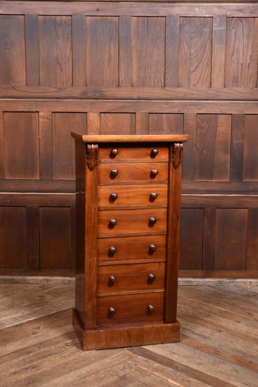 A tall Victorian mahogany Wellington chest featuring seven graduated drawers with turned knobs and a carved side locking pilaster. View III