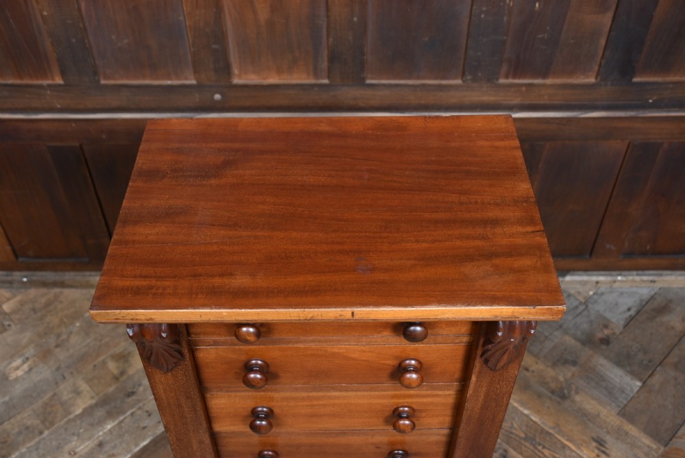 A tall Victorian mahogany Wellington chest featuring seven graduated drawers with turned knobs and a carved side locking pilaster. View VI