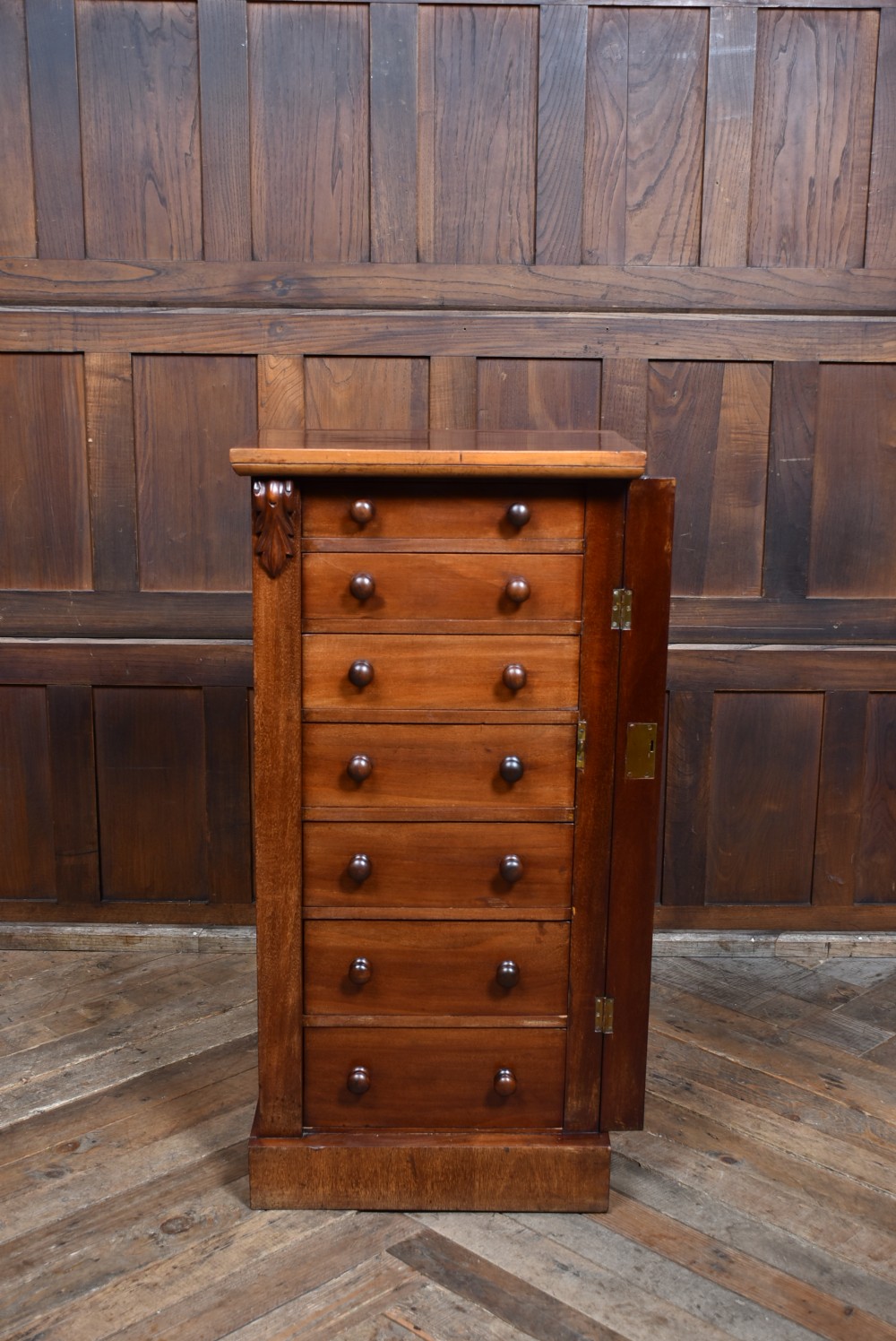 A tall Victorian mahogany Wellington chest featuring seven graduated drawers with turned knobs and a carved side locking pilaster. View IX