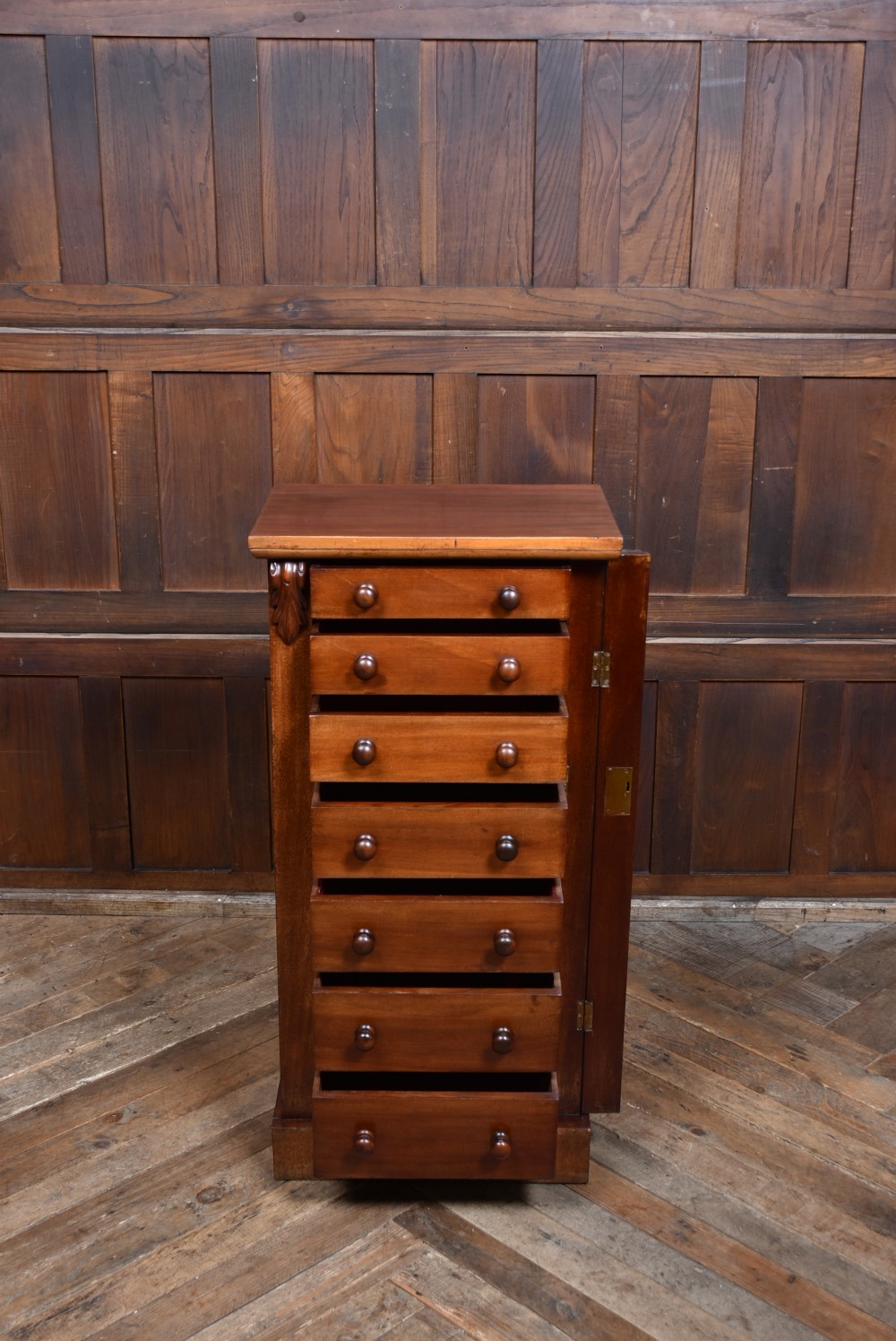 A tall Victorian mahogany Wellington chest featuring seven graduated drawers with turned knobs and a carved side locking pilaster. View X