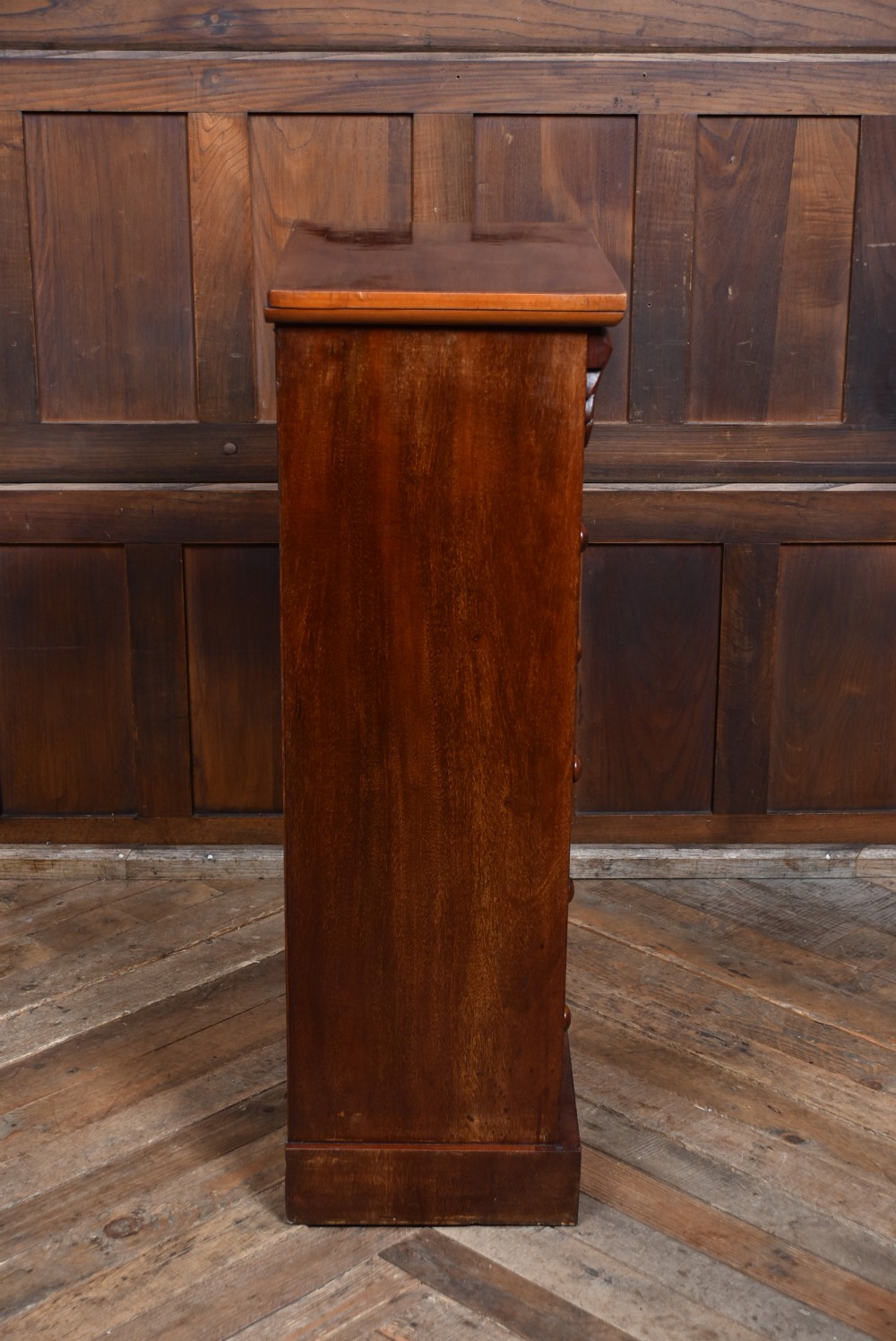 A tall Victorian mahogany Wellington chest featuring seven graduated drawers with turned knobs and a carved side locking pilaster. View XIII