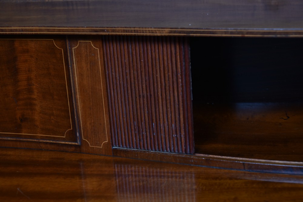 An Edwardian mahogany sideboard featuring satinwood string inlay, a curved central drawer, flanking cupboard doors, a raised superstructure, and square tapered legs. View XII