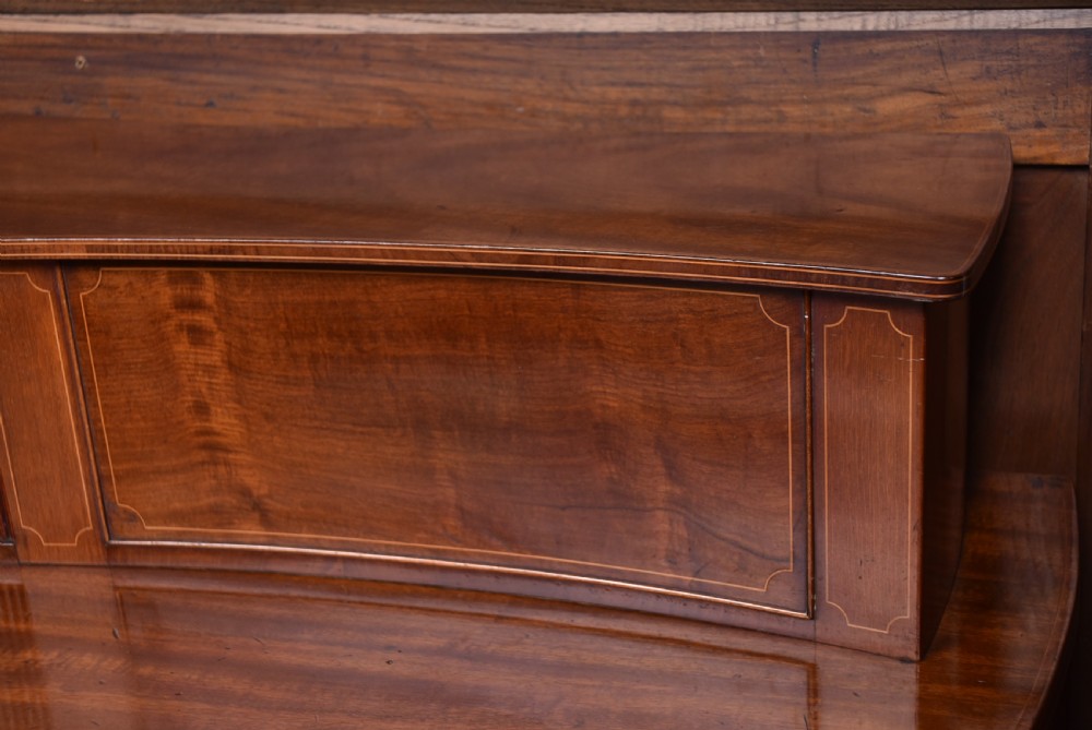 An Edwardian mahogany sideboard featuring satinwood string inlay, a curved central drawer, flanking cupboard doors, a raised superstructure, and square tapered legs. View XIII