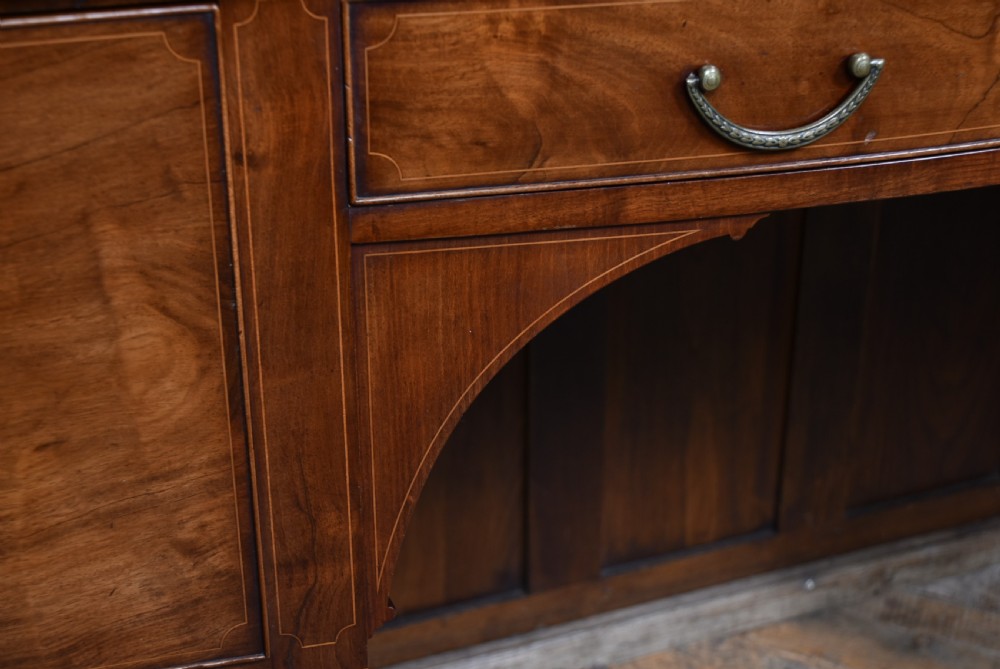 An Edwardian mahogany sideboard featuring satinwood string inlay, a curved central drawer, flanking cupboard doors, a raised superstructure, and square tapered legs. View XVI