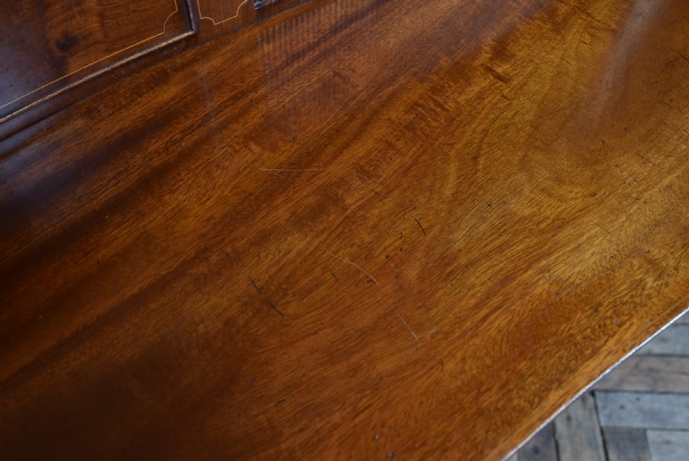 An Edwardian mahogany sideboard featuring satinwood string inlay, a curved central drawer, flanking cupboard doors, a raised superstructure, and square tapered legs. View XVIII