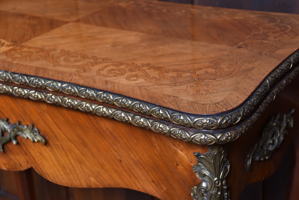 A Victorian Louis XV style marquetry card table featuring cabriole legs, brass mounts, a serpentine apron, and a fold-over top. View VI