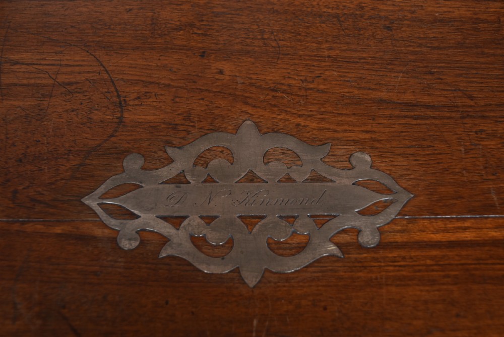 A nineteenth-century rectangular teak coffer with flush brass corner brackets, brass escutcheons, and an inlaid top cartouche, raised on a wooden stand with square legs. View VIII
