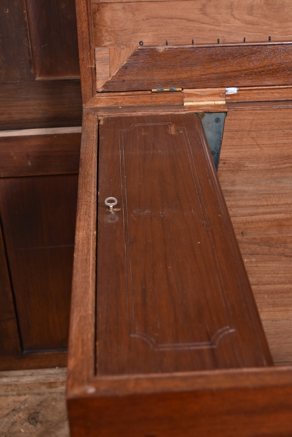 A nineteenth-century rectangular teak coffer with flush brass corner brackets, brass escutcheons, and an inlaid top cartouche, raised on a wooden stand with square legs. View XIV