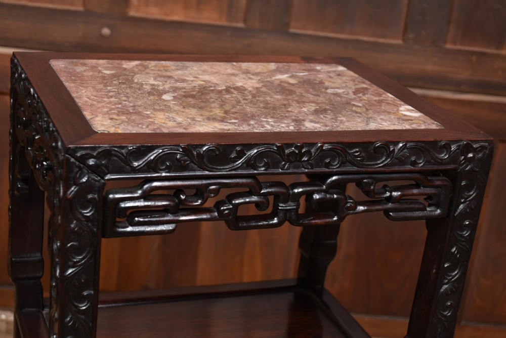 A tall dark hardwood Chinese side table featuring an inset pink marble top, intricately carved apron, two lower tiered shelves, and carved feet. View IV