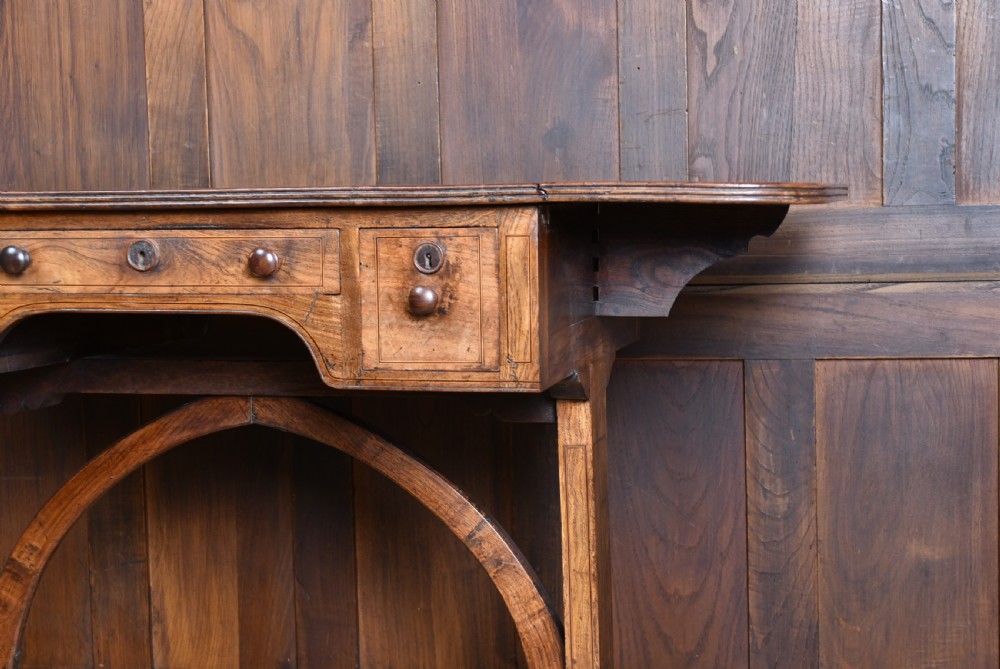 A Regency rosewood sofa table featuring a crossbanded drop-leaf top, shallow drawers with wooden knobs, curved trestle legs, and brass castors. View IX