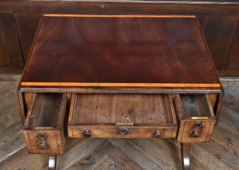 A Regency rosewood sofa table featuring a crossbanded drop-leaf top, shallow drawers with wooden knobs, curved trestle legs, and brass castors. View XVIII