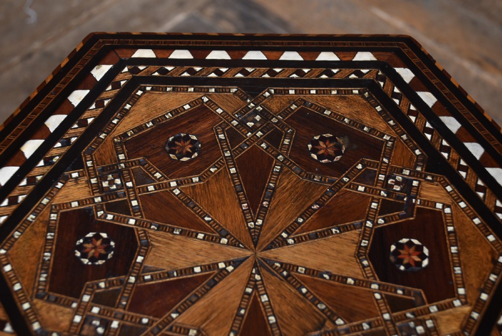 A hexagonal wooden side table featuring geometric star marquetry inlay, bone accents, Moorish arch aprons, and turned legs with a lower star stretcher. View IX