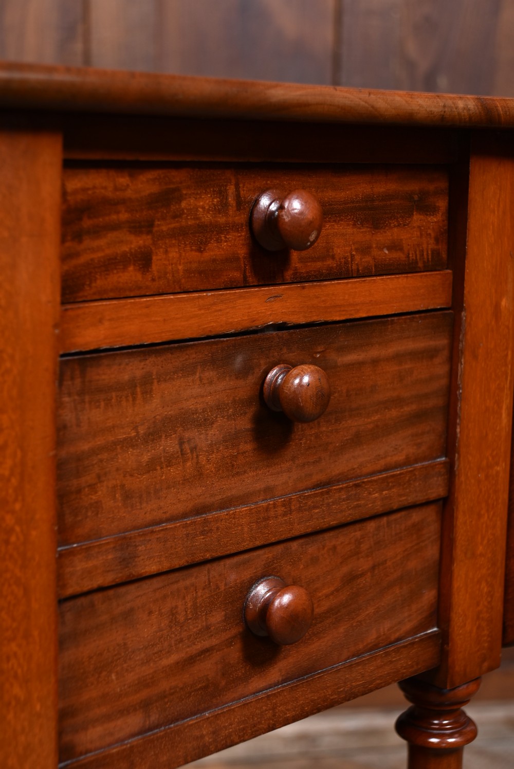 A Victorian mahogany drop-leaf table featuring three small drawers with wooden knobs, turned legs, a lower shelf, and brass castors. View XII