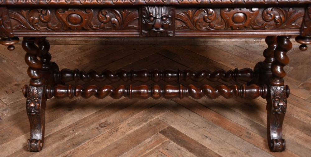 A Victorian carved dark oak writing table featuring a central Green Man mask, inset leather writing surface, and barley twist stretchers. View III