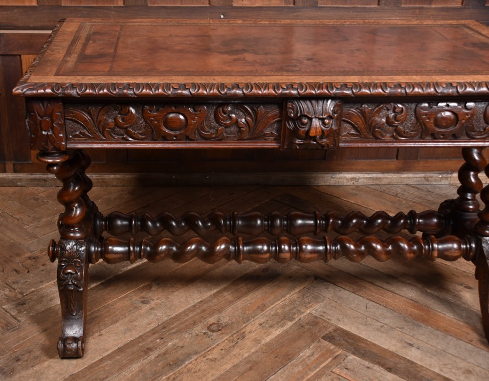 A Victorian carved dark oak writing table featuring a central Green Man mask, inset leather writing surface, and barley twist stretchers. View XI